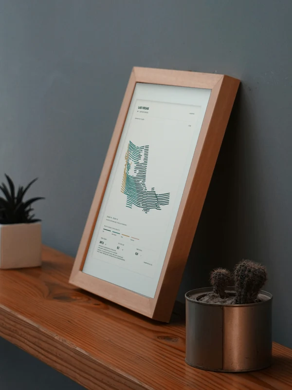 The Las Vegas artwork digitally placed in a frame on a shelf beside plants. Framing and proportions are illustrative.