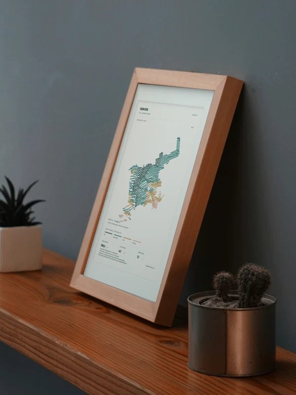 The Denver artwork digitally placed in a frame on a shelf beside plants. Framing and proportions are illustrative.